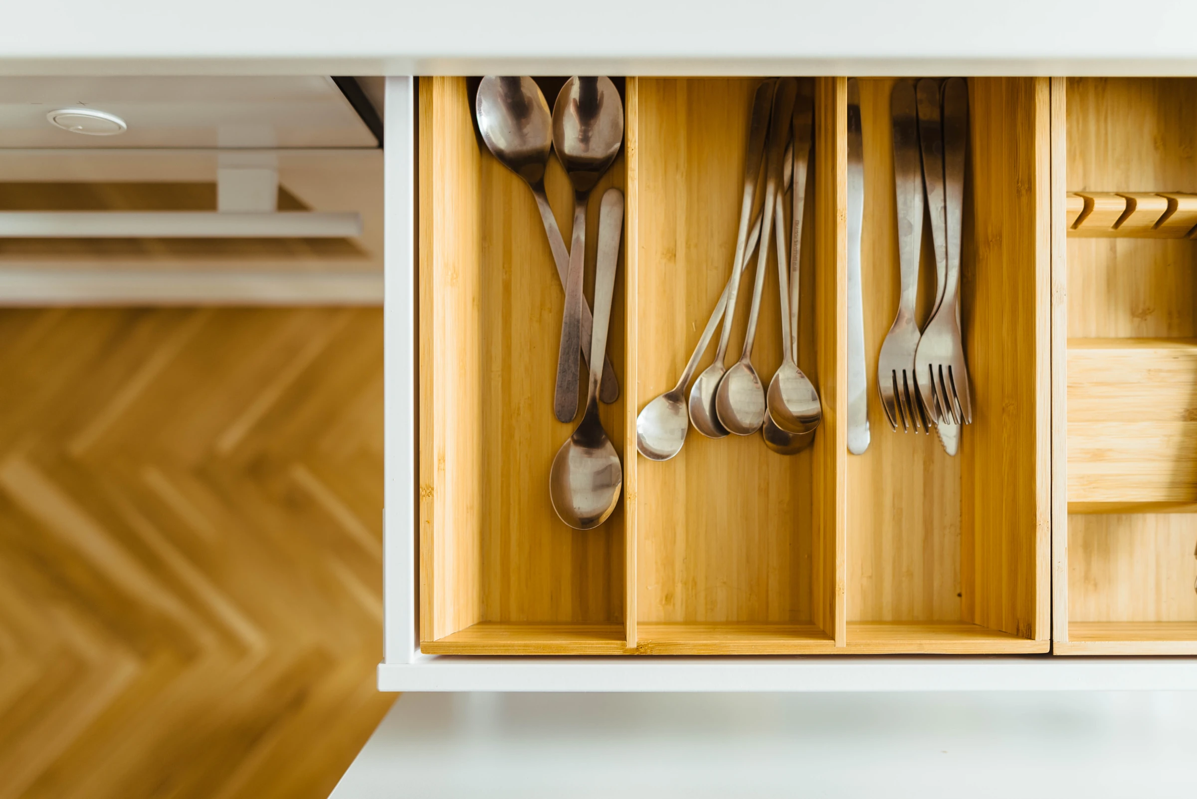 Wooden cutlery divider in a contemporary white kitchen drawer.